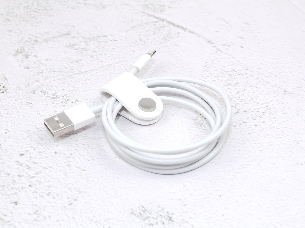 A white pebbled-grain faux leather cord wrap with a snap closure, displayed on a textured background.